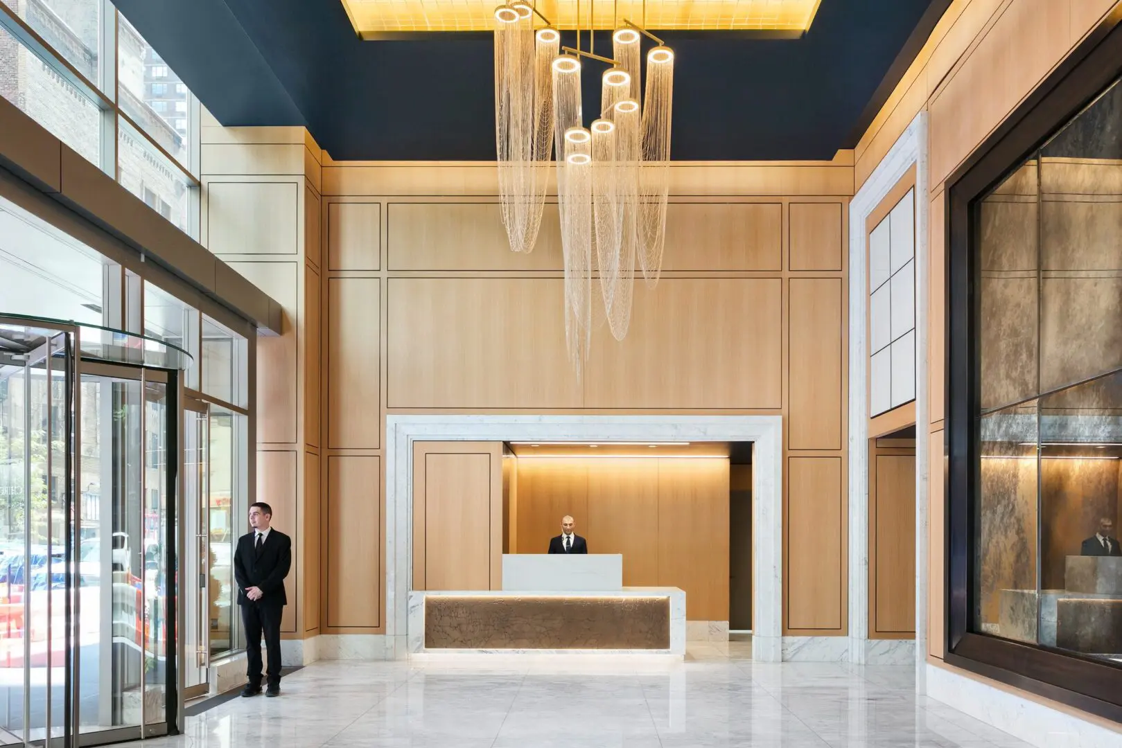 Modern hotel lobby with chandelier and concierge.