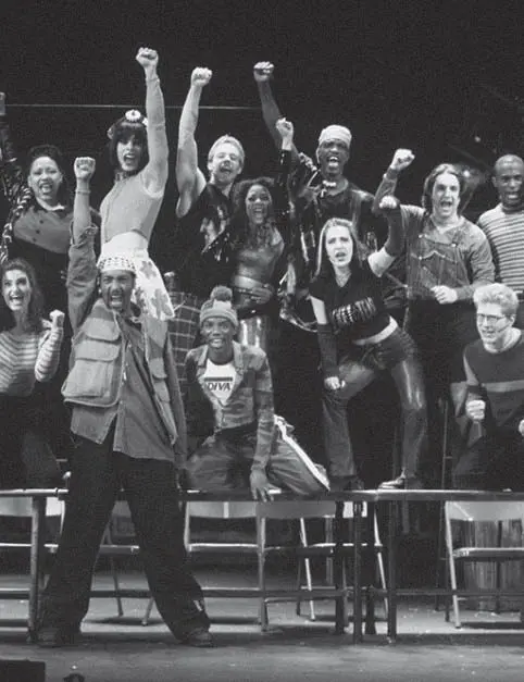 Group of performers raising fists on stage.