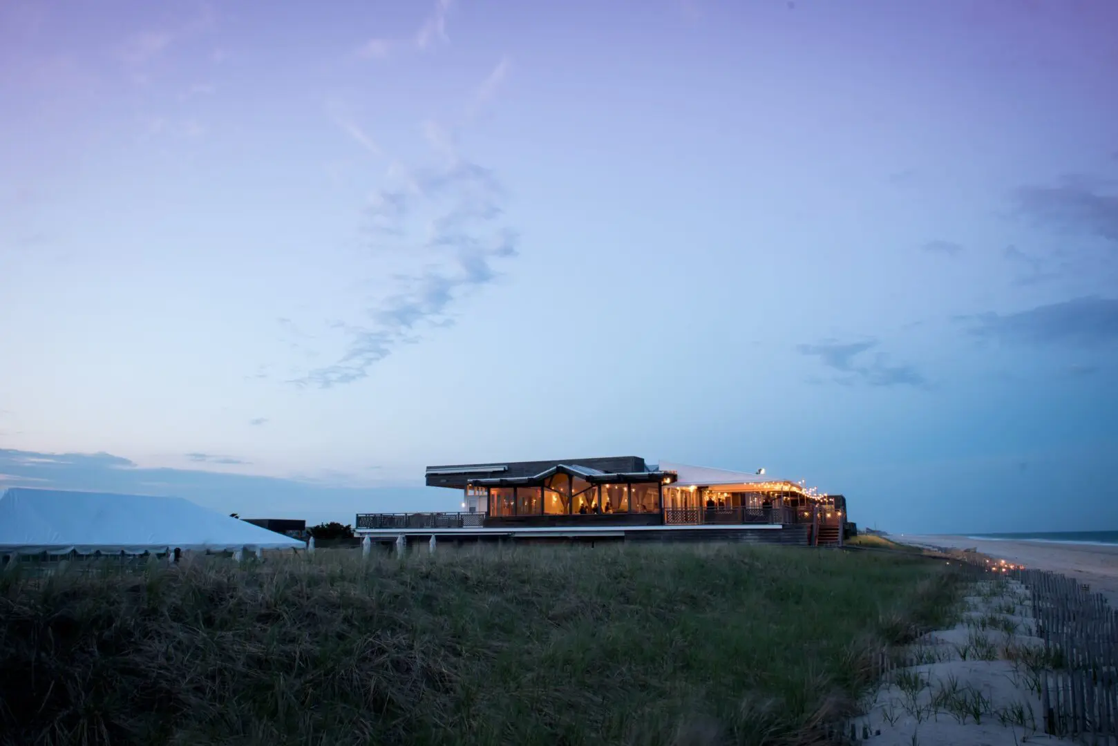 Beachfront building with lights at twilight.