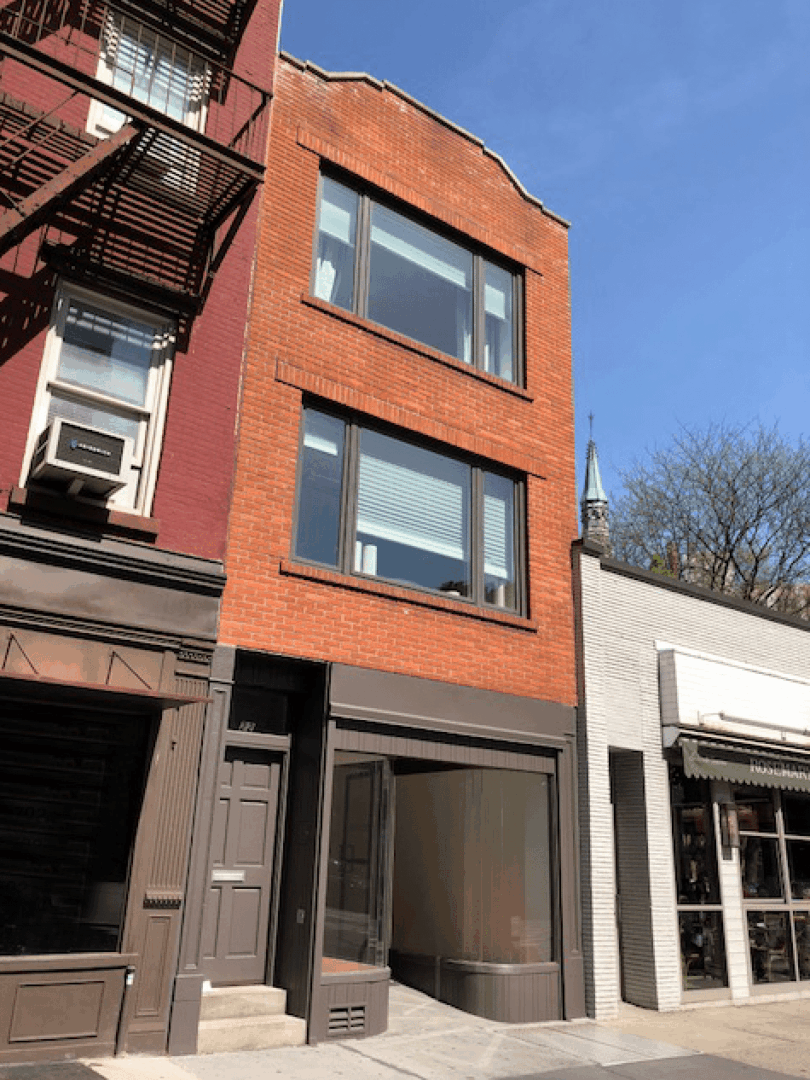 Three-story red brick building on street.