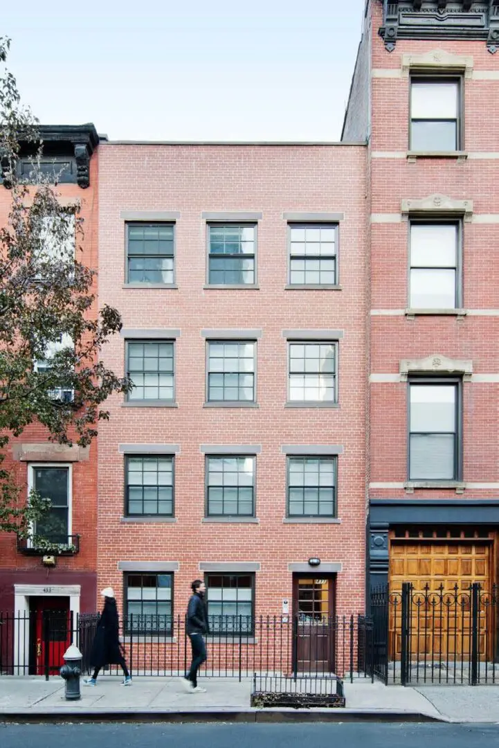 Red brick building with two people walking.